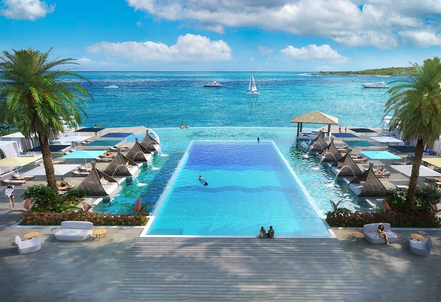 A resort pool with daybeds and palm trees overlooking the Caribbean Sea