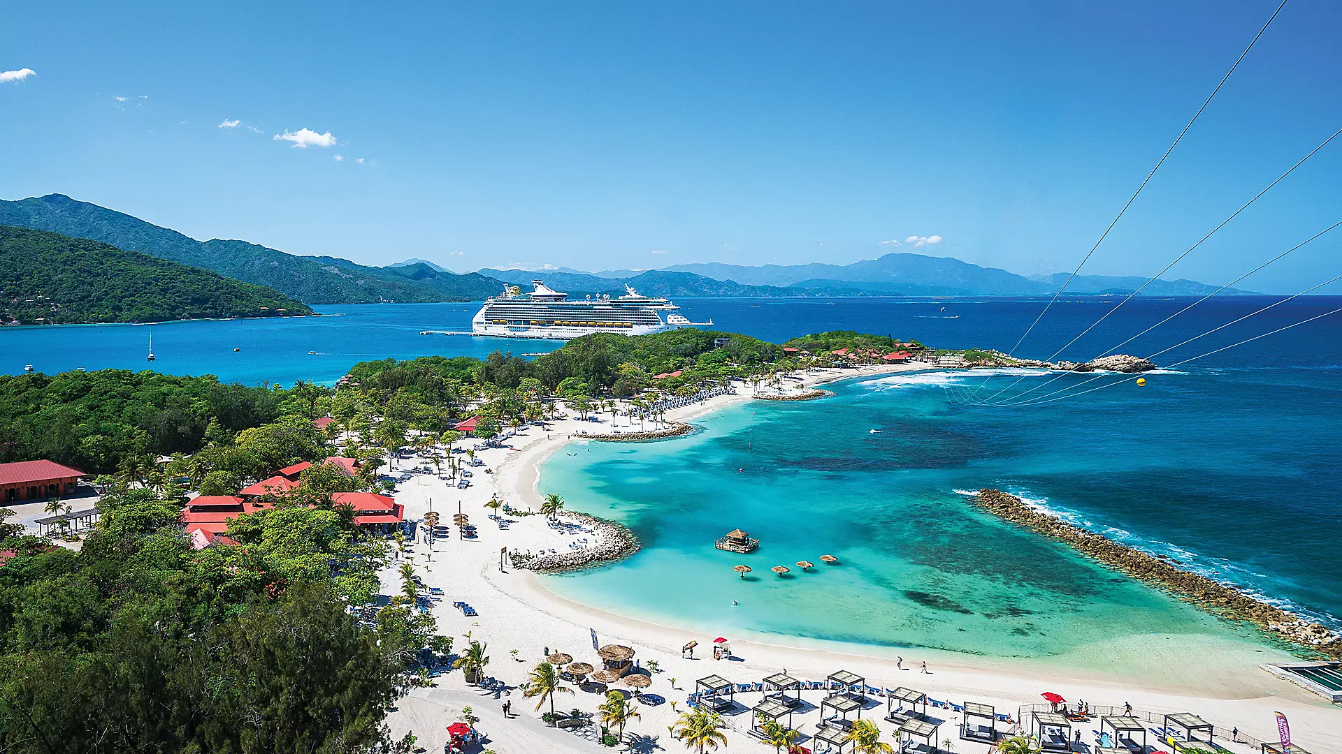 A Labadee beach with white sand, turquoise water and loungers beneath sea-grape trees