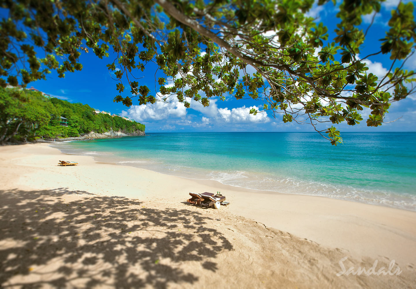 A secluded Sandals beach with white sand, turquoise water and loungers shaded by trees