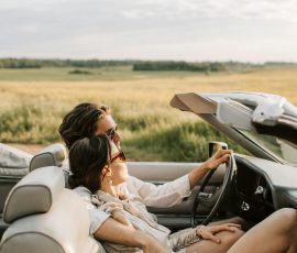 Europe A couple enjoys a romantic drive through scenic fields in a stylish convertible.